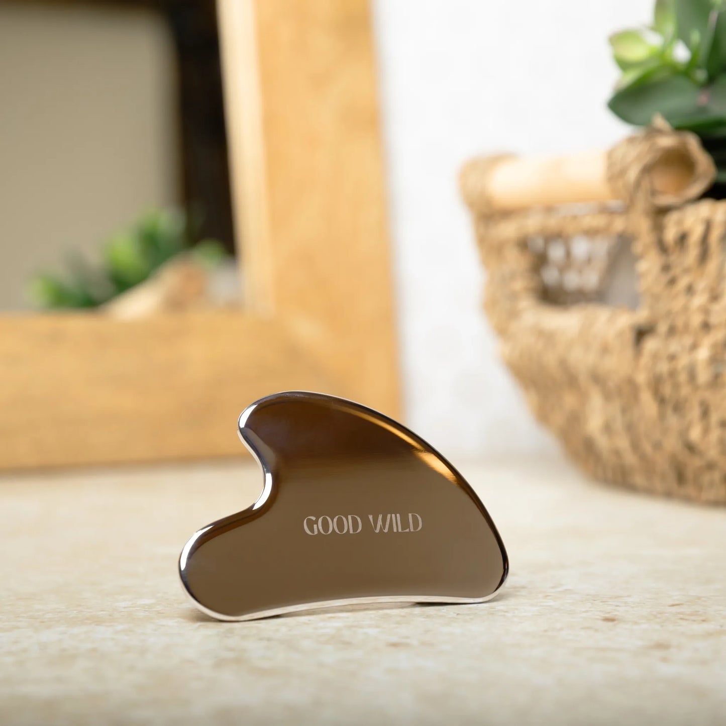 Gua Sha tool with 'GOOD WILD' branding on a wooden surface.