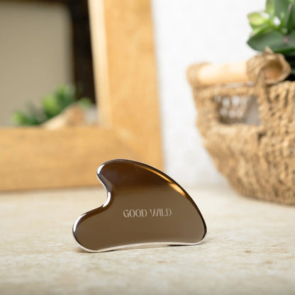 Gua Sha tool with 'GOOD WILD' branding on a wooden surface.