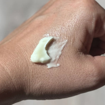 Hand with a small amount of cream on the palm against a neutral background